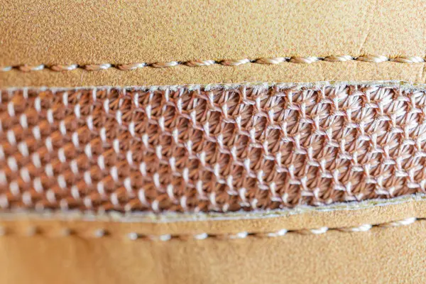 Deri ürün üzerinde titiz dikiş detaylarını vurgulayan yakın plan görüntü kalitesi ve işçiliği vurguluyor