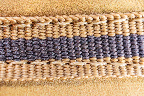 Görüntü, çeşitli renk ve dokuma yapısına sahip iki bandı gösteren karmaşık dokuma kumaşı gösteriyor. Modada, iç tasarımda veya geleneksel sanatsal wor 'da kullanılan kalite işçiliğini gösteriyor.