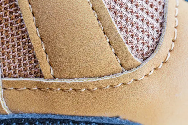 Kahverengi deri ayakkabı dikişlerinin yakın plan görüntüsü, yumuşak ışıklandırılmış derinlikteki kaliteli işçilik.