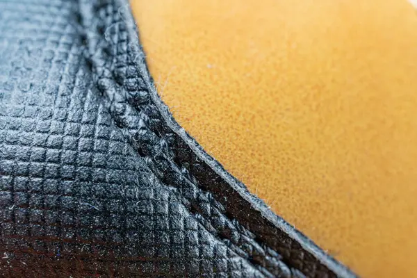 Yüksek kaliteli, muhtemelen mobilya ya ya da moda aksesuarları olan, açık arkaplan dokusuna karşı koyu dikişe odaklı yüksek kaliteli bir malzemenin yakın plan görüntüsü derimsi görünür ve görüntü kaliteyi gösterir