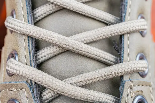 Beyaz ya da krem rengi, pruvada örülmüş ayakkabı danteli, muhtemelen açık hava ortamında, ayakkabı bağcığı kancası ile kolayca ulaşılabilir.