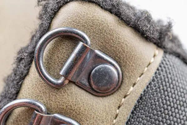 Dayanıklılık için sağlam bağcıkları ve metal kancaları olan engebeli kahverengi açık hava ayakkabıları. Maceracıları, yürüyüşçüleri ve açık hava meraklılarını hedef alıyor.