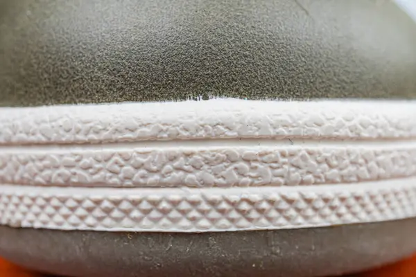 Beyaz, gri ve siyah bir renk eğimine sahip desenli, kavrayıcı kauçuk tabanlı engebeli bir açık hava ayakkabısı.