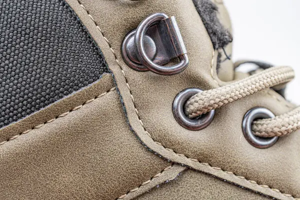 Sağlam bir yürüyüş botunun, süet ve deri sentetik kumaşla yakın plan çekimi, metal tokalar, nötr bir arka plan vurgulanabilirliğine karşı gösterilir.