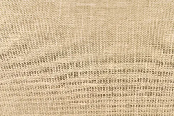 Yumuşak desenli yüzeyi olan, doğal tonlu, yüksek kaliteli bir kumaşın yakın plan görüntüsü, muhtemelen ev eşyaları, moda aksesuarları veya iç tasarım pazarlama malzemelerinde kullanılıyor.