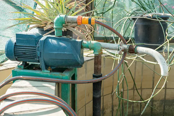 Motosikletli bir pompa ve hortumların yer aldığı açık hava fotoğraflarına göre, bu görüntü, pazarlama malzemelerinde kullanılmak üzere muhtemelen bir çocuk odası yakınında endüstriyel ya da tarımsal bir ortam oluşturuyor.