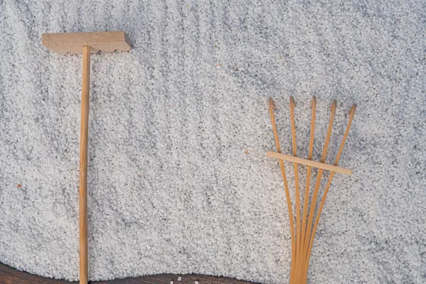 Görüntü bir süpürge ve faraş ile bölünmüş bir ekran gösteriyor, her ikisi de kapalı alan temizliği için doğal ahşap araçlar, dokulu bir duvara karşı.