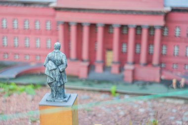 Görüntü, merkezde muhtemelen önemli bir tarihi veya kültürel figürü temsil eden büyük neoklasik bui Kyiv, Ukrayna 06-11-2024 ile şehir parkı veya bahçesinde bronz bir heykel sergiliyor.
