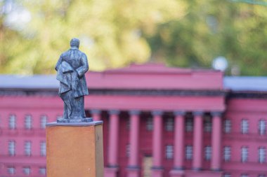 Önemli bir şahsın merkez heykelinin yer aldığı görkemli, tarihi bir hükümet binası. Bina kırmızıdır ve yeşilliğin ortasında durur. Kyiv, Ukrayna 06-11-2024