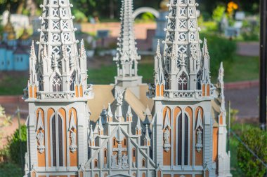 Yüksek kuleler, uçan payandalar, sivri kemerler ve süslü heykellerle karakterize edilmiş küçük ölçekli gotik bir katedral modeli bir parkta veya bahçede sergilenmiştir.