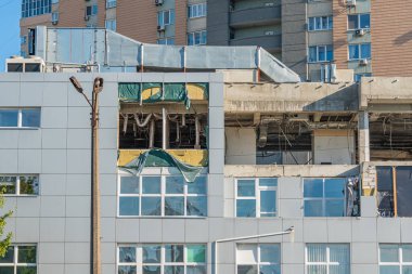 Görüntü iki zıt bina cephesini gösteriyor - biri hasarsız beyaz, birden fazla kat, dikdörtgen pencereler, balkon veya teras, renkli camlı sürgülü kapılar ve başka bir pa Kyiv, Ukrayna 06-11-2024