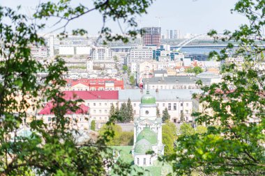 Yeşillik tarafından çerçevelenmiş geleneksel ve modern mimariye sahip bir Avrupa şehir manzarası, açık gökyüzü altında Kyiv, Ukrayna 06-11-2024