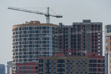 Modern, çok katlı bir bina, inşa halinde, modüler yapı teknikleri sergileniyor. Yapının sağlam, topraksı bir cephesi ve üniformalı pencereleri var. Kyiv, Ukrayna 06-11-2024