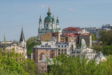 Canlı bir şehir manzarası, tarihi ve modern mimarinin bir karışımını sergiliyor. Üzerinde Bizans dizaynı Kyiv, Ukrayna 06-11-2024 'ü andıran mavi kiremitli bir kubbe bulunuyor.