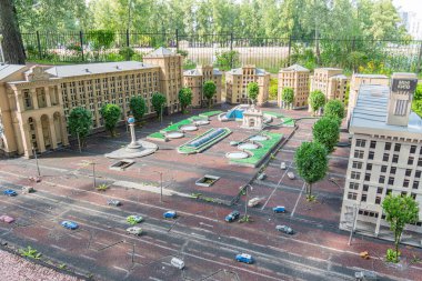 Toprak tonlarında büyük, simetrik, neoklasik bir Palladyen binanın detaylı bir minyatür modeli, muhtemelen açık kamusal alanı ve Kyiv, Ukrayna 06-11-2024 'ü çevreleyen kentsel bir çevreyi tasvir ediyor.