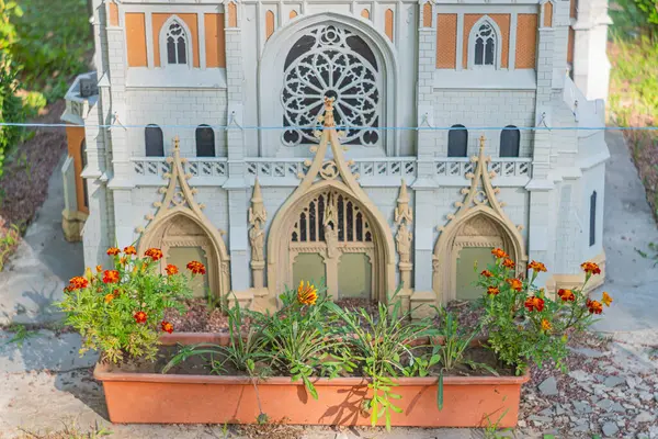 Büyük bir gül penceresi olan Gotik Uyanış minyatür bir model, karmaşık çatı temizliği ve renkli bir bahçe Kyiv, Ukrayna 06-11-2024