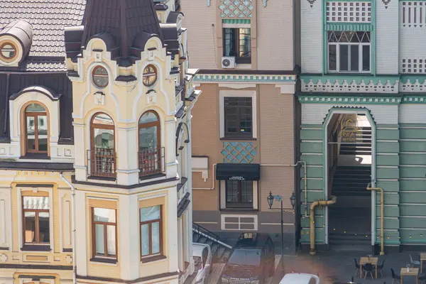 19. yüzyıldan önceki dönemlere kadar değişen çeşitli mimari tarzları sergileyen üç farklı binanın yer aldığı Avrupa şehir manzarasını tasvir eden bir resim.