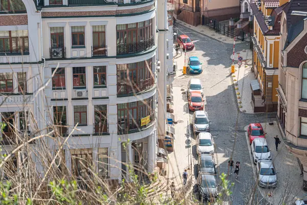 Görüntü, Avrupa 'nın tarihi bir sokak manzarasını bir binanın çatısından gösteriyor. Sahne, eski mimari yapılar, kaldırım taşı sokakları, araçlar, yayalar, sokak Kyiv, Ukrayna 06-11-2024