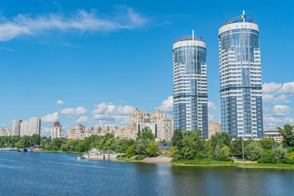 İki çarpıcı cam gökdelenin temiz gökyüzünü yansıttığı modern bir şehir manzarası. Ön plandaki durgun su Kyiv, Ukrayna 06-11-2024 'e huzur katıyor.