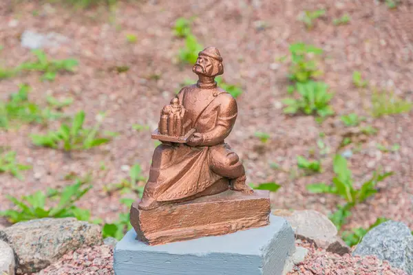 Çakıl taşlarının arasına yerleştirilmiş ve geleneksel kıyafetlerle süslenmiş taş bir heykel, tarihi ya da kültürel bağlamda kırmızı-kahverengi kil heykeli Kyiv, Ukrayna 06-11-2024