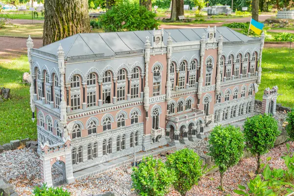 Resim, kemerli pencereleri, kubbeleri, balkonları ve Yunan mimari unsurları olan beyaz, çok katlı geleneksel bir binanın ayrıntılı bir modelini gösteriyor.