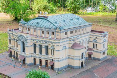 Beyaz, klasik mimariden esinlenilmiş, birden fazla kemerli ve dikdörtgen pencereli, pediatri, sütun ve dekoratif unsurlara sahip minyatür bir bina modeli.