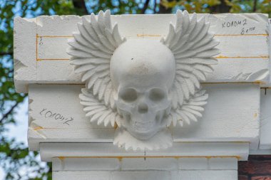 Yıpranmış, kanatlı bir kafatası tasarımı olan beton bir yapıya yakından bakınca yüzeydeki metin ve numaralar bakım ve onarım amaçlarını gösteriyor. Muhtemel olarak Kyiv, Ukrayna 06-11-2024