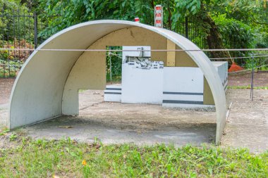 Görüntü modern, kavisli bir beton yapıyı tasvir ediyor, muhtemelen bir park ortamında barınak ya da sanat tesisi olarak hizmet veriyor. Çelik kirişlerle desteklenen çatı Kyiv, Ukrayna 06-11-2024