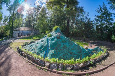 Bir görüntüde, alçak bir duvarla çevrili yıpranmış bir taş tepe, yakınındaki bir kubbe, yeşil ve patikaların bulunduğu bir park ya da bahçe alanı, h Kyiv, Ukrayna 06-11-2024