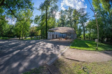 Çağdaş bir parktaki modern bir pavyon, şeffaf bir çatı ve karanlık duvarlara sahip bina temiz hatlar ve yol kenarına yerleştirilmiş en az süsleme ile çalışır, Kyiv, Ukrayna 06-11-2024