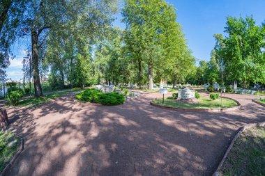 Ağaçlarla çevrili ve çimlerle çevrili merkezi simetrik plazalı iyi korunmuş bir park veya bahçe çeşitli bitkiler, basit mimari ve Kyiv, Ukrayna 06-11-2024