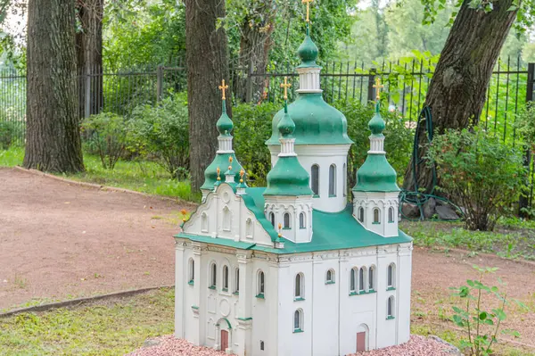 Bir minyatür Ortodoks kilise modeli geleneksel Ukrayna mimarisini çeşitli kubbeler, haçlar ve yeşil-altın renkli bir şema ile sergiliyor. Parktaki s Kyiv, Ukrayna 06-11-2024 gibi bir yerde sergileniyor.