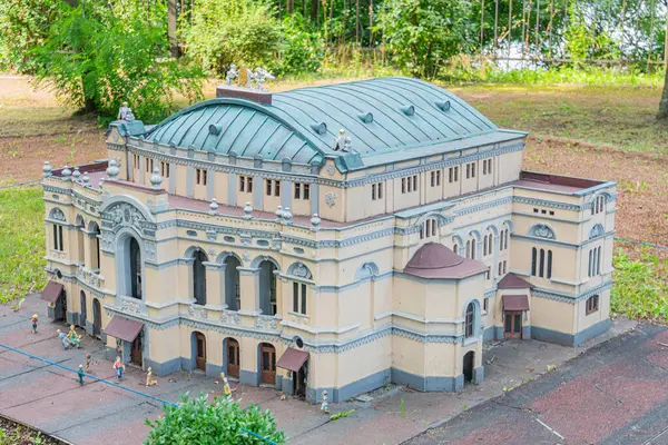 Beyaz, klasik mimariden esinlenilmiş, birden fazla kemerli ve dikdörtgen pencereli, pediatri, sütun ve dekoratif unsurlara sahip minyatür bir bina modeli.