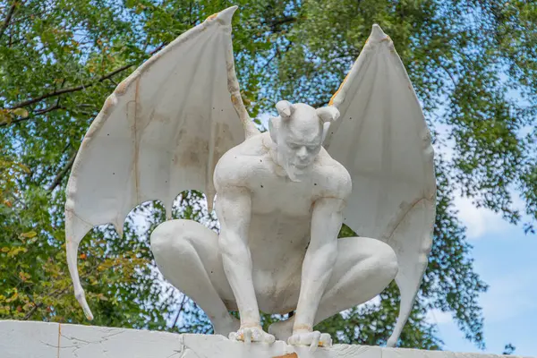 Melez bir insan-yarasa yaratığın heykeli, dizayn konseptiyle sorunsuz bir şekilde bütünleşmiş bir yapının tepesine yerleştirilmiş. Heykel, kanatlarını açmış ve abartılı insan Kyiv, Ukrayna 06-11-2024