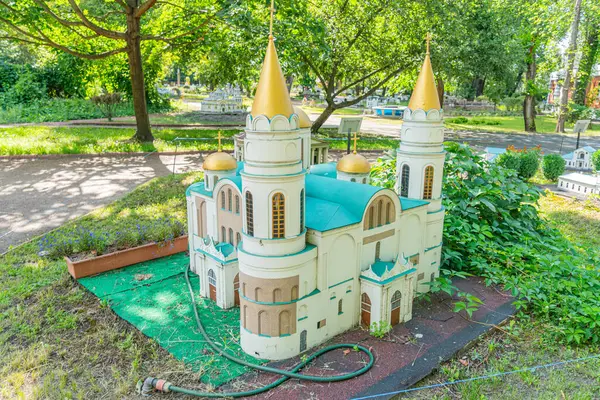 Minyatür bir cami modelinde simetrik İslami mimari, iki altın süslemeli minareler, canlı mavi çatı işaretleri, huzurlu bir bahçede veya Kyiv, Ukrayna 06-11-2024