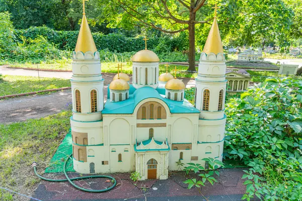 Minyatür bir cami modelinde simetrik İslami mimari, iki altın süslemeli minareler, canlı mavi çatı işaretleri, huzurlu bir bahçede veya Kyiv, Ukrayna 06-11-2024
