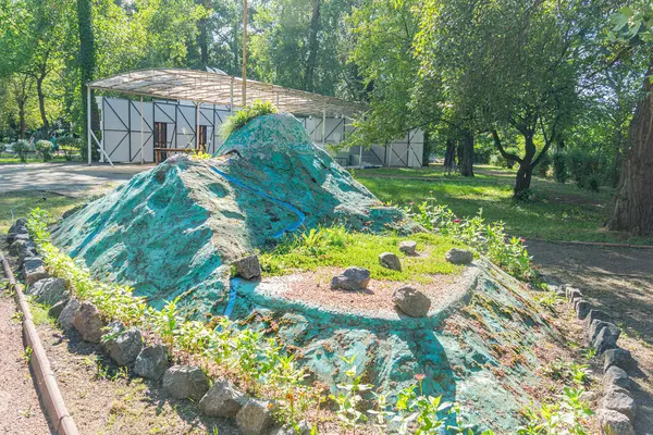 Doğal jeolojik oluşumları andıran insan yapımı bir kaya oluşumu, peyzajlı bir alana kurulmuştur. Yapı çevresine uyum sağlamak için yeşile boyanmıştır ve bir Kyiv, Ukrayna 06-11-2024 vardır.