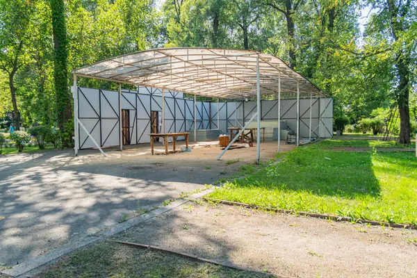 Parktaki cambaz ayaklıklarının üzerinde modern, açık çatılı bir pavyon, ahşap banklar ve doğal çevreye sahip, güneşli bir gün Kyiv, Ukrayna, 06-11-2024