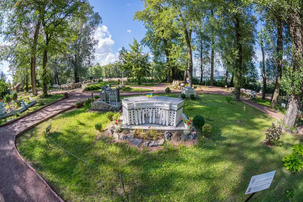 Yeşillik ve çakıl zemini ile çevrili bir Yunan Uyanış çardağı ile büyüleyici bir park manzarası. Çardağın pergola bir çatısı var, Doric sütunları gibi, ve davetkar bir şekilde Ukrayna, 06-11-2024