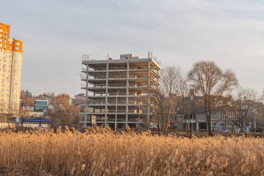 Şehir gelişiminin ortasında, yemyeşil ile çevrili bir şehir siluetine karşı inşa edilmiş bir apartman, doğal ve kentsel g Kyiv, Ukrayna, 03-29-2025 karışımını vurguluyor.