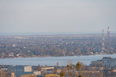 Bina, su veya göl karışımlı kentsel şehir manzarası muhtemelen nehir veya göl, elektrik hatları, endüstriyel element ve pazarlama materyali Kyiv, Ukrayna, 03-29-2025 için uygun manzara cazibesi