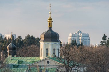 Ukrayna 'nın başkenti Kyiv' de ya da tarihi bir bölgede yer alan modern şehir siluetine zıt olarak altın kubbeleri ve kuleleri olan bir Doğu Ortodoks kilisesinin hava görüntüsü.