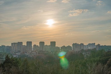 Gökdelenli binalar ve bitki örtüsüyle güzel bir şehir, gün batımında görülebilen bu görüntü, çeşitli mimari tarzlara sahip hareketli bir kentsel alan olduğunu gösteriyor, ve Kyiv, Ukrayna, 03-29-2025