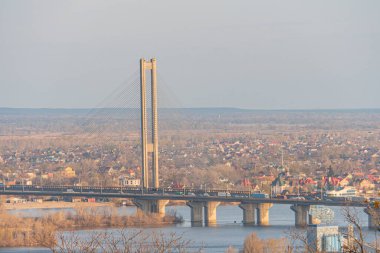 Uzak toprakları birbirine bağlayan sakin suların üzerindeki ahenkli bir köprünün havadan görünüşü bağlantı ve doğal güzellik hissi veriyor: Kyiv, Ukrayna, 03-29-2025