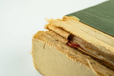 Yıpranmış sayfaları olan eski bir kitap, eşsiz tarihini ve kalıcı güzelliğini sergileyen beyaz bir yüzeyde yatar.