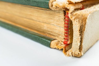 Yıpranma ve aşınma izlerini gösteren eski bir kitabın resmi. Sayfalarının koyu kenarlardan merkeze doğru renk eğrisi var. Bu da uzun zaman önce dik olarak depolandığını gösteriyor.