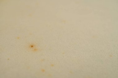 Yakından çekilmiş, koyu benekli, kumlu, açık gri bir yüzey görüntüsü.