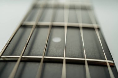 Akustik bir fretboard 'un yakın plan görüntüsü, hassasiyetini ve yankısını gözler önüne seriyor. Enstrümandaki işçiliği ve detaylara olan dikkati vurguluyor.