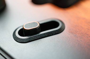 Pürüzsüz, koyu renk elektronik cihaz yan paneli. İki düğmesi ve dahili yuvası var.