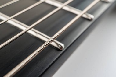 Gitar, fretboard ve telleri gösteren yakın plan görüntü, hassasiyet, zanaat, dayanıklılık, tonsal nitelikler ve fretboard, string ve boyun gibi anahtar bileşenleri vurguluyor.
